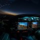 Lightened up cockpit and avionics in aircraft flying at night with beautiful twilight in background